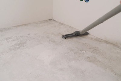 Cleaning cement floor with vacuum cleaner.